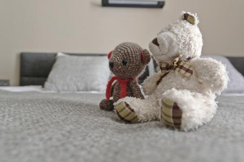 two stuffed teddy bears sitting on a bed at Deribas Hotel in Odesa