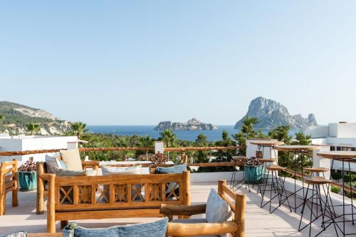 a patio area with chairs, tables, and benches at Petunia Ibiza - Adults Only in Cala Vadella