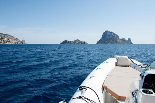 a boat in the water with two islands in the background at Petunia Ibiza, a Beaumier hotel in Cala Vadella