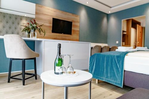 ハーネンクレー・ボックスヴィーゼにあるHaus am See Luxury HS 228 Bのベッド、テーブル、ワイン1本が備わる客室です。