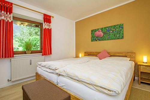 ライト・イム・ヴィンクルにあるFerienwohnung Schmankerlのベッドルーム1室(ベッド1台付)、赤いカーテン付きの窓が備わります。