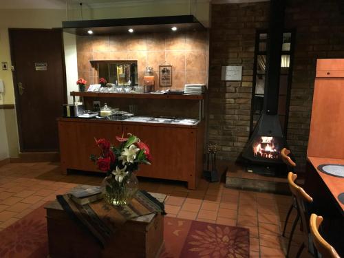 a kitchen with a fireplace and a table with flowers at De Oude Herberg in Centurion
