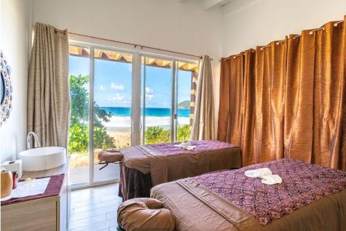 a room with two beds and a view of the beach at Wyndham Tortola BVI Lambert Beach Resort in East End