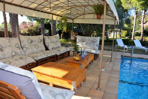 um pátio com sofás e uma mesa ao lado de uma piscina em Villa Sitges El Ranch Amaizing Outdoor Areas Beaches at 5 minutes walk Sitges at 15 min drive AC Pool Jacuzzi & Garden XXL em Calafell