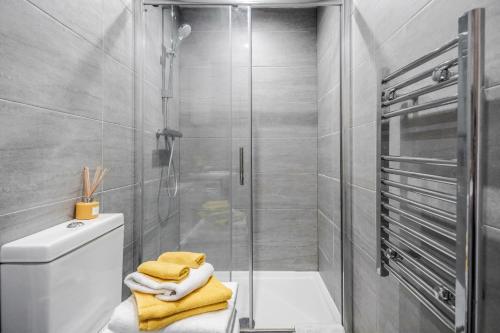 a bathroom with a shower and a toilet with towels at Modernview Serviced Accommodation 1 Bedroom Watford HighStreet F10 in Watford