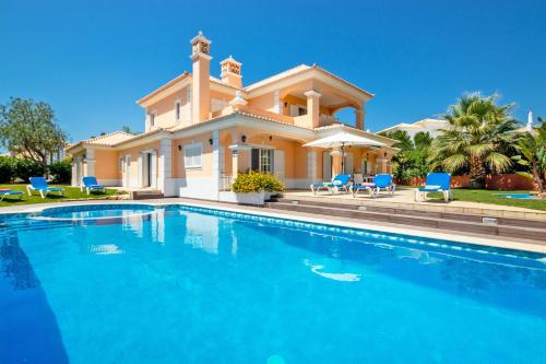 a villa with a swimming pool in front of a house at Villa Savannah by Algarve Vacation in Almancil