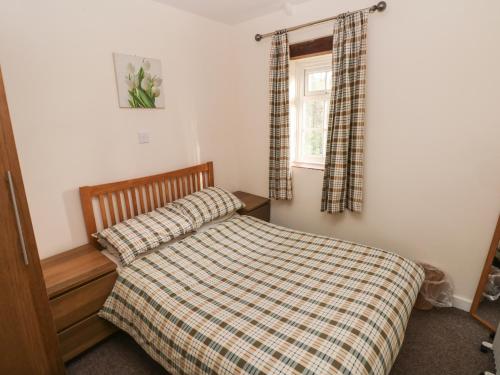 a bedroom with a bed with a checkered blanket and a window at Knap Cottage in Walton East