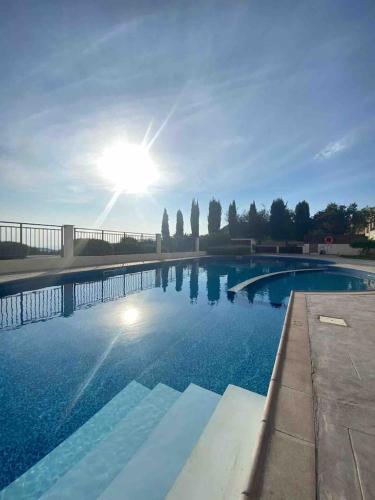 una gran piscina con el sol en el cielo en Aphrodite Gardens, en Pissouri
