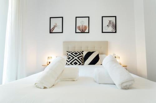 AlohaMundi Almansa II في إشبيلية: غرفة نوم بيضاء مع سرير أبيض مع وسائد بيضاء