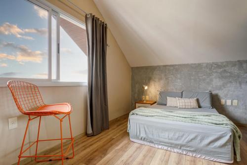 a bedroom with a bed and a chair and a window at Triplex com jacuzzi na melhor vista de Floripa! in Florianópolis