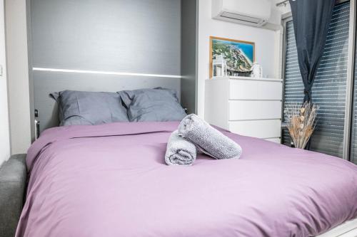 a bedroom with a purple bed with towels on it at TI TAHITI STUDIO-3MIN PLAGE-TERRASSE COSY-WIFI-PARKING - TOP PROS SERVICESConciergerie La Grande Motte in La Grande-Motte