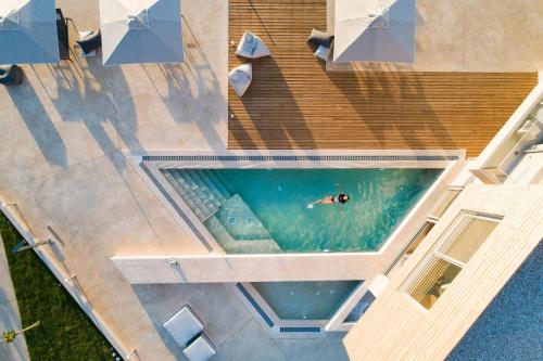 An intimate Villa Resort- Right on the beach, by ThinkVilla في Petres: اطلالة علوية لشخص يسبح في المسبح