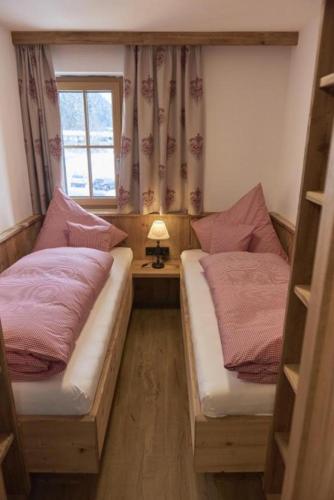 two beds in a small room with a window at Berghotel Birkenhof GmbH in Reit im Winkl