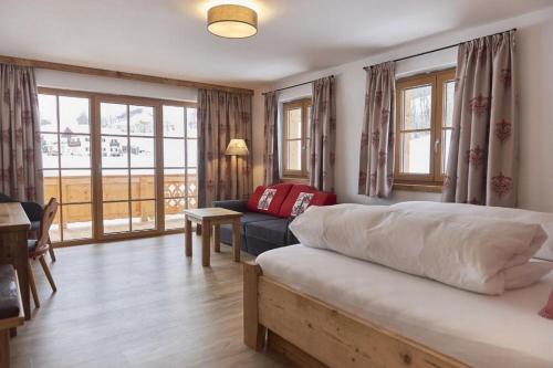 a bedroom with a bed and a couch and windows at Berghotel Birkenhof GmbH in Reit im Winkl
