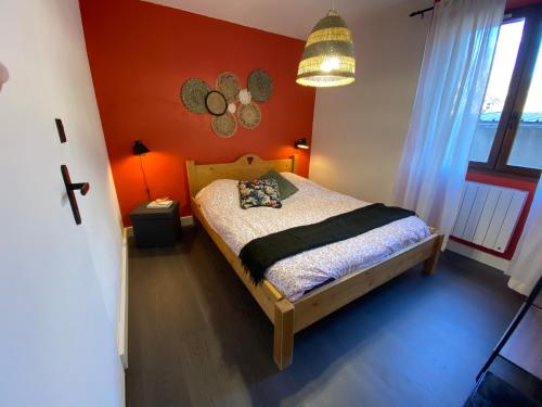 a bedroom with a bed with an orange wall at Appartement douillet, proche gare, terrasse, cave in Saint-Jean-de-Maurienne