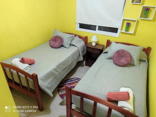 two beds in a room with yellow walls at Casa 5-6 Personas Puerto Natales in Puerto Natales