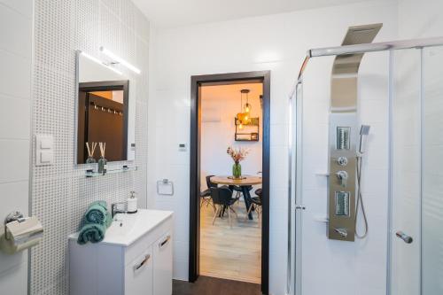 a bathroom with a shower and a sink and a table at BlackWood '66 Apartman in Siófok