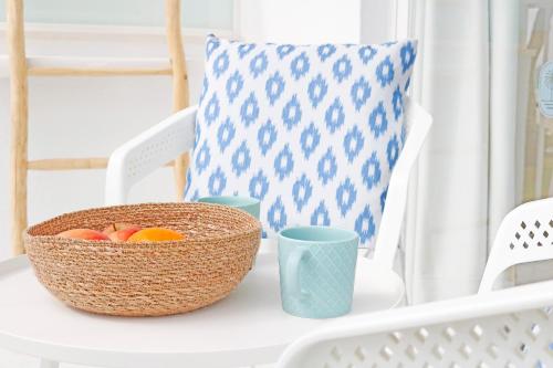 a basket of fruit on a white table with cups at Bonavida Apartments in Port d'Alcudia