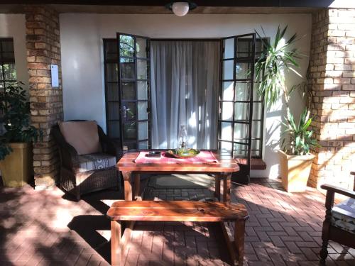 a patio with a wooden table and a chair at De Oude Herberg in Centurion