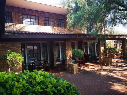 a brick building with tables and chairs in a courtyard at De Oude Herberg in Centurion