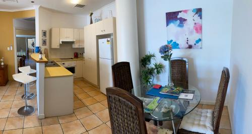 a kitchen and dining room with a glass table and chairs at Tropical One Bedroom Apartment at The Mediterranean in Port Douglas