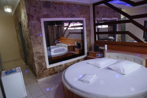 um quarto com uma cama branca e um espelho grande em Desejo Motel em Araçoiaba da Serra