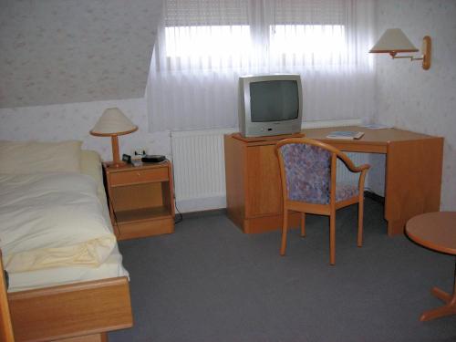 a bedroom with a bed and a desk with a tv at Gasthof Siller in Spiegelberg