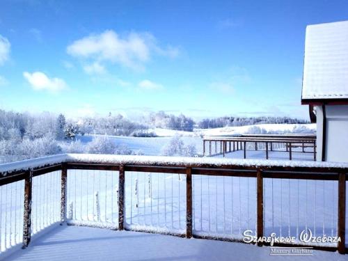 a balcony covered in snow with a view of a lake at Szarejkowe Wzgórza in Szarejki