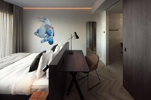 a bedroom with a bed with a desk and a wall at Van der Valk Hotel Beveren in Beveren