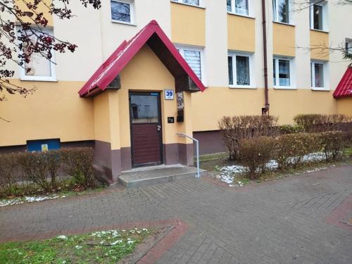 un edificio con una puerta marrón con techo rojo en Mieszkanie M3, en Szczytno