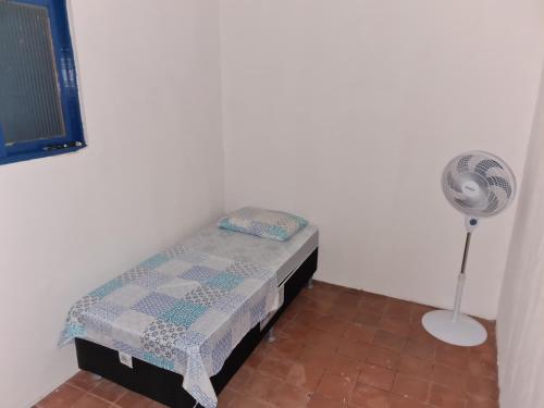 a small room with a small bed and a fan at Santorini Flats in Arraial do Cabo
