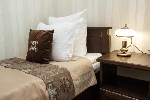a bed with white pillows and a table with a lamp at GasthauS & SPA in Bukovel
