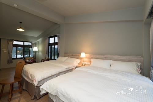 2 camas en una habitación de hotel con sábanas blancas en Bi La Homestay en Luye