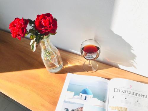 a vase of roses and a glass of wine on a table at Villa Fotini in Firostefani