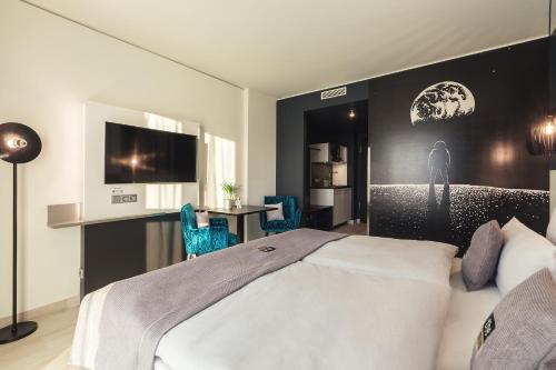 a bedroom with a large white bed and a desk at the niu Star - Apartments in Sindelfingen