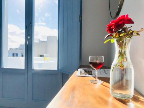 a vase with a red rose and a glass of wine at Villa Fotini in Firostefani