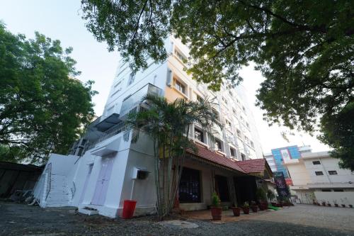 a white building with a palm tree in front of it at Hotel Palmyra Grand Inn in Tirunelveli