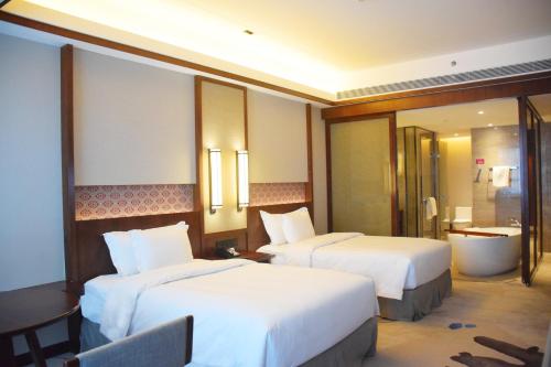 a hotel room with two beds and a bathroom at Howard Johnson Neodalle Resort Zhangjiajie in Zhangjiajie