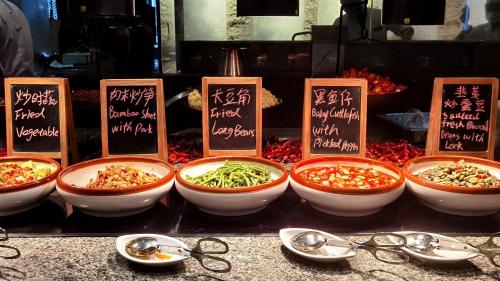 a group of bowls of food on a table with signs at Howard Johnson Neodalle Resort Zhangjiajie in Zhangjiajie