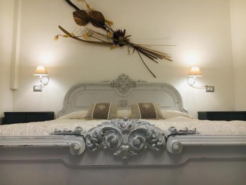 una camera da letto con un letto bianco e un fiore sul muro di B&B SHARDANA a Sennori