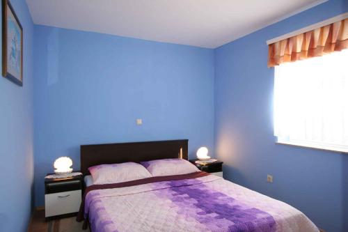 ein blaues Schlafzimmer mit einem Bett mit einer lila Decke in der Unterkunft Apartment Soline 2 in Soline
