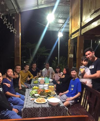 een groep mensen die rond een tafel zitten met eten bij mai chau rice fields homestay in Mai Chau
