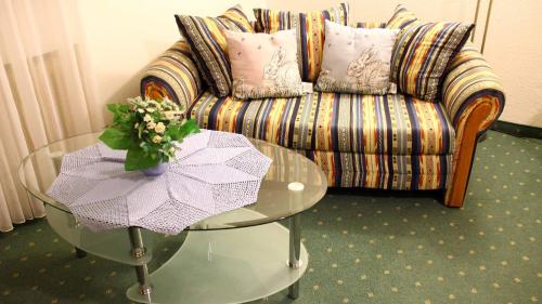 a living room with a couch and a glass table at Hotel Gasthof Zum weissen Lamm in Hohenberg an der Eger