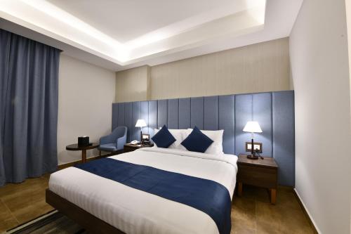 a bedroom with a large bed with blue and white sheets at JUFFAIR BOULEVARD HOTEL & SUITES in Juffair