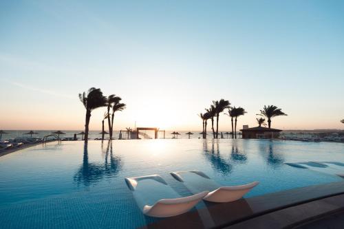 Cancun Sokhna Resort & Villas في العين السخنة: مسبح مع كراسي الصالة والنخيل