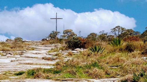 una cruz en la cima de una colina con un camino de tierra en Palácio do Sol Hostel Pousada, en São Thomé das Letras