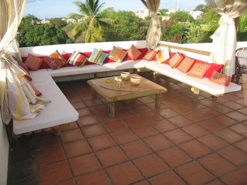 a white couch with colorful pillows on a patio at Villa Osumare Guest House in Flic-en-Flac