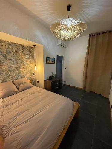 une chambre avec un grand lit et un lustre dans l'établissement Appart 110m2 terrasse climatisé quartier médiéval, à Clermont-Ferrand