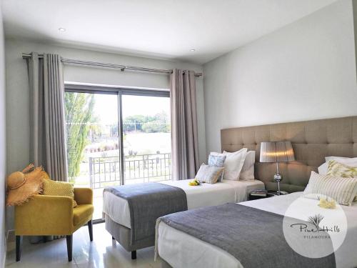 1 dormitorio con 2 camas, silla y ventana en Pine Hills Resort en Quarteira