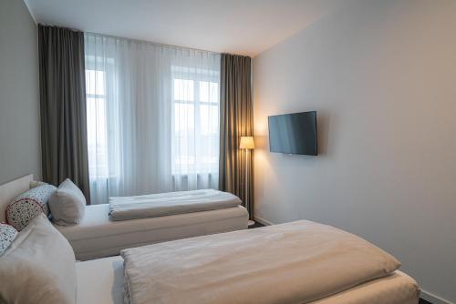 a hotel room with two beds and a flat screen tv at BIG MAMA Leipzig in Leipzig